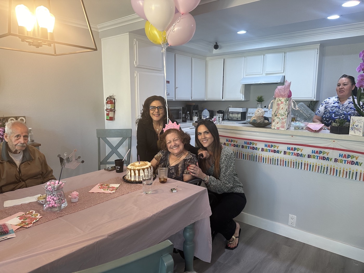 Family birthday celebration around a table with cake, balloons, and decorations.
