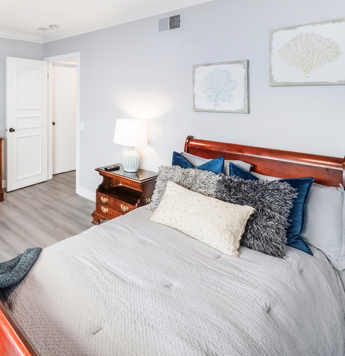 Cozy bedroom with wooden bedframe, plush pillows, and elegant decor.