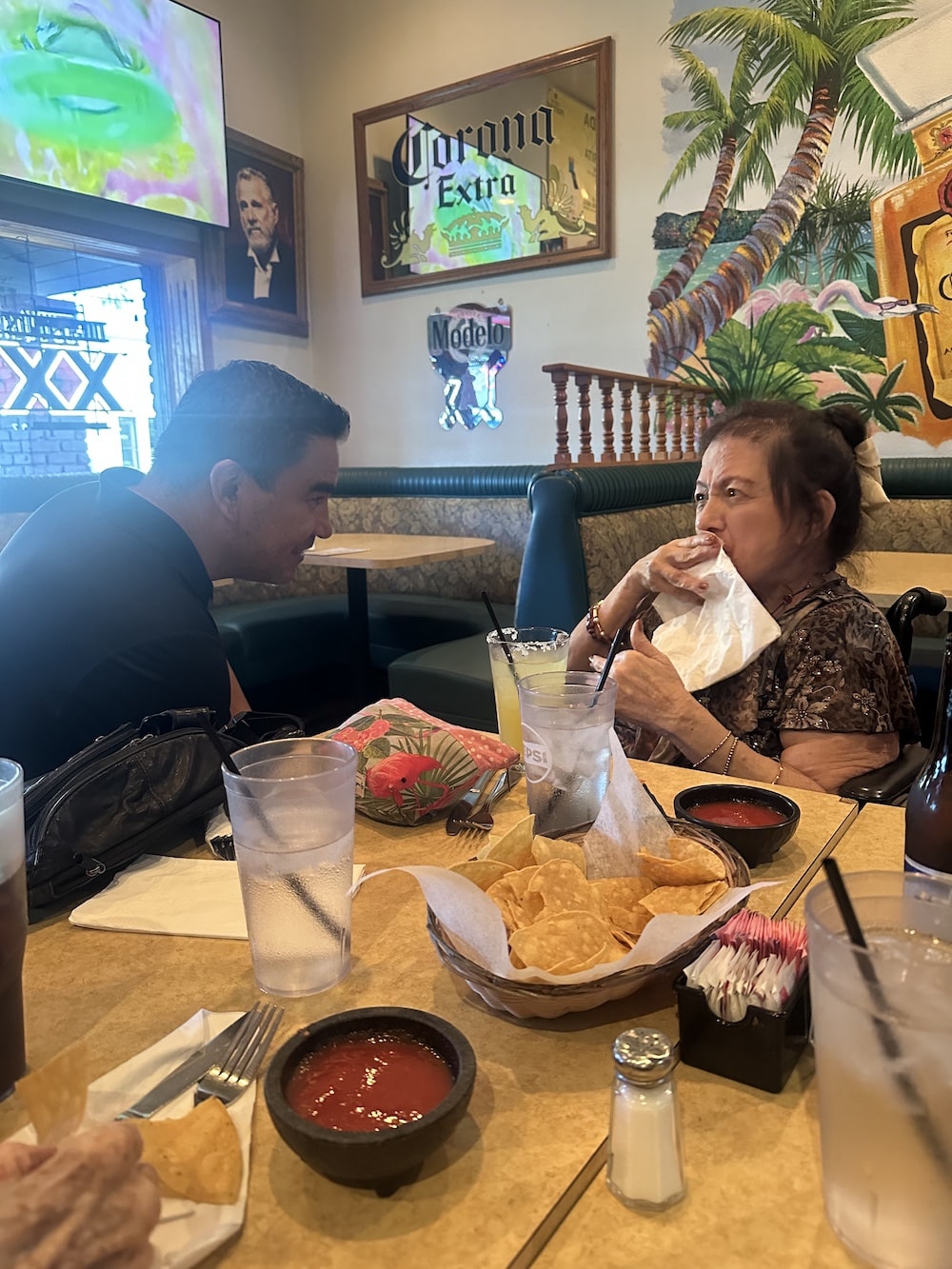 A person sitting with an older woman at a restaurant, enjoying chips and salsa.